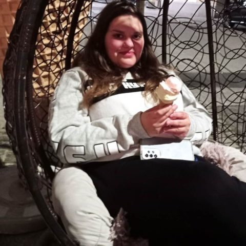 Kristina Štrekelj sedi na gugalniku s sladoledom v roki.